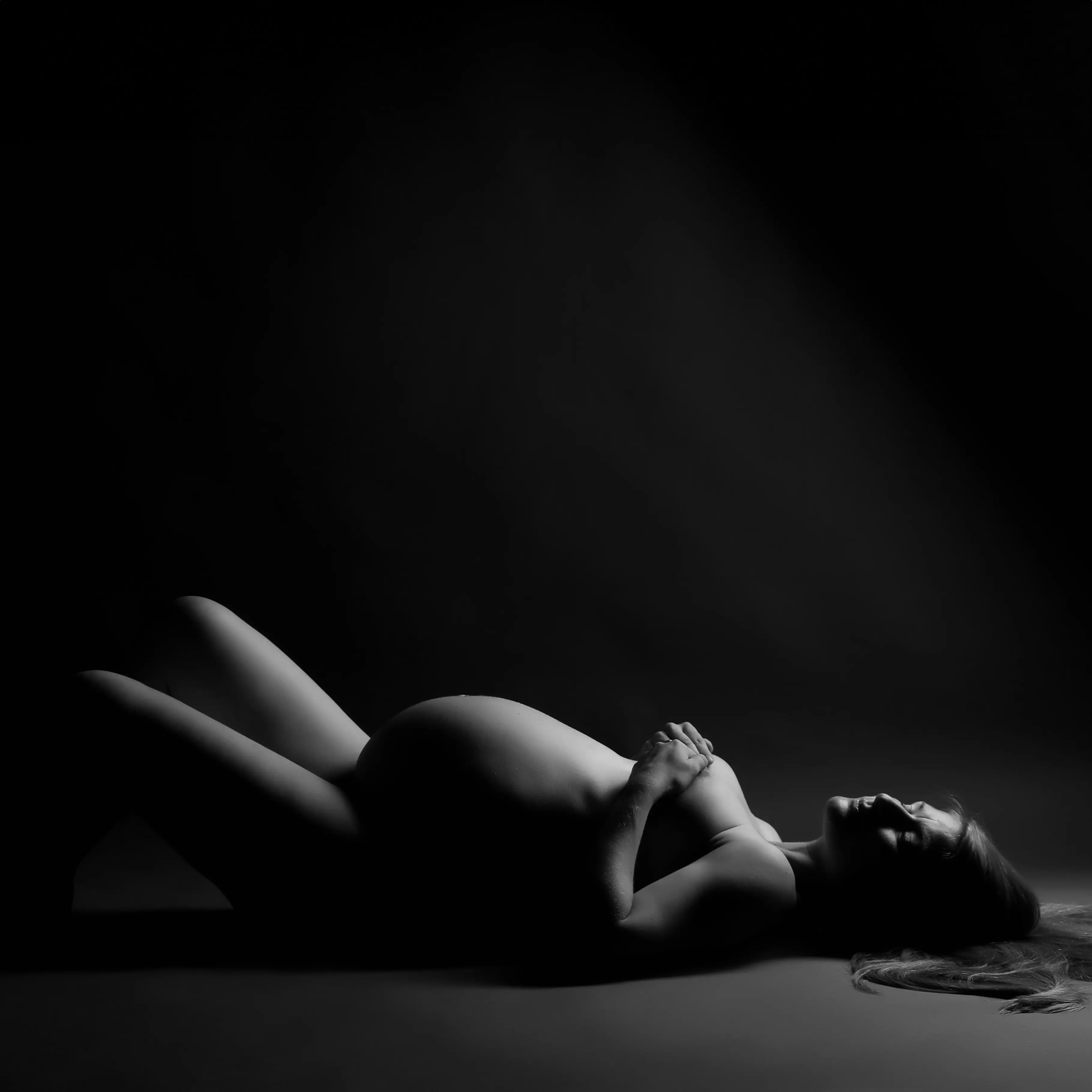 Schwangere liegend in dramatischem Low-Key