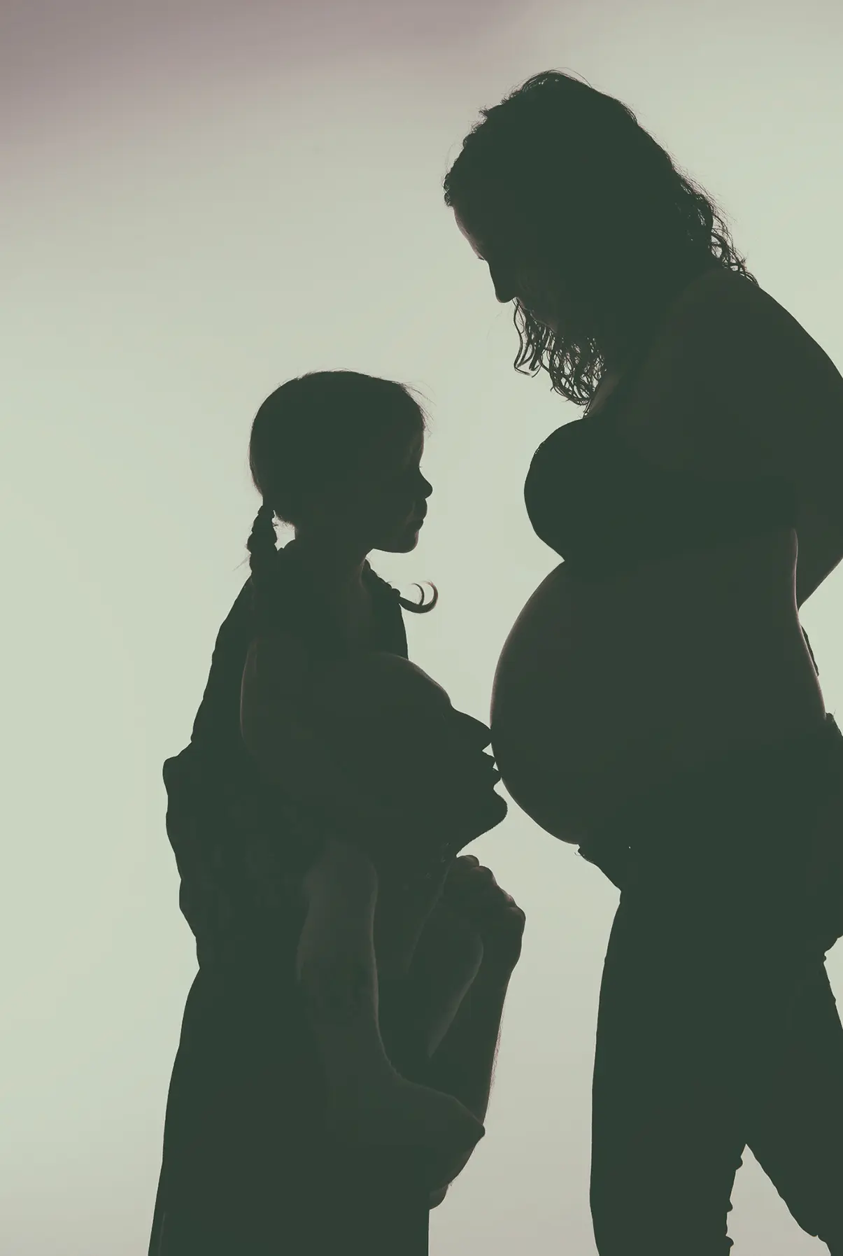 Silhouette einer schwangeren Mutter mit kleiner Tochter
