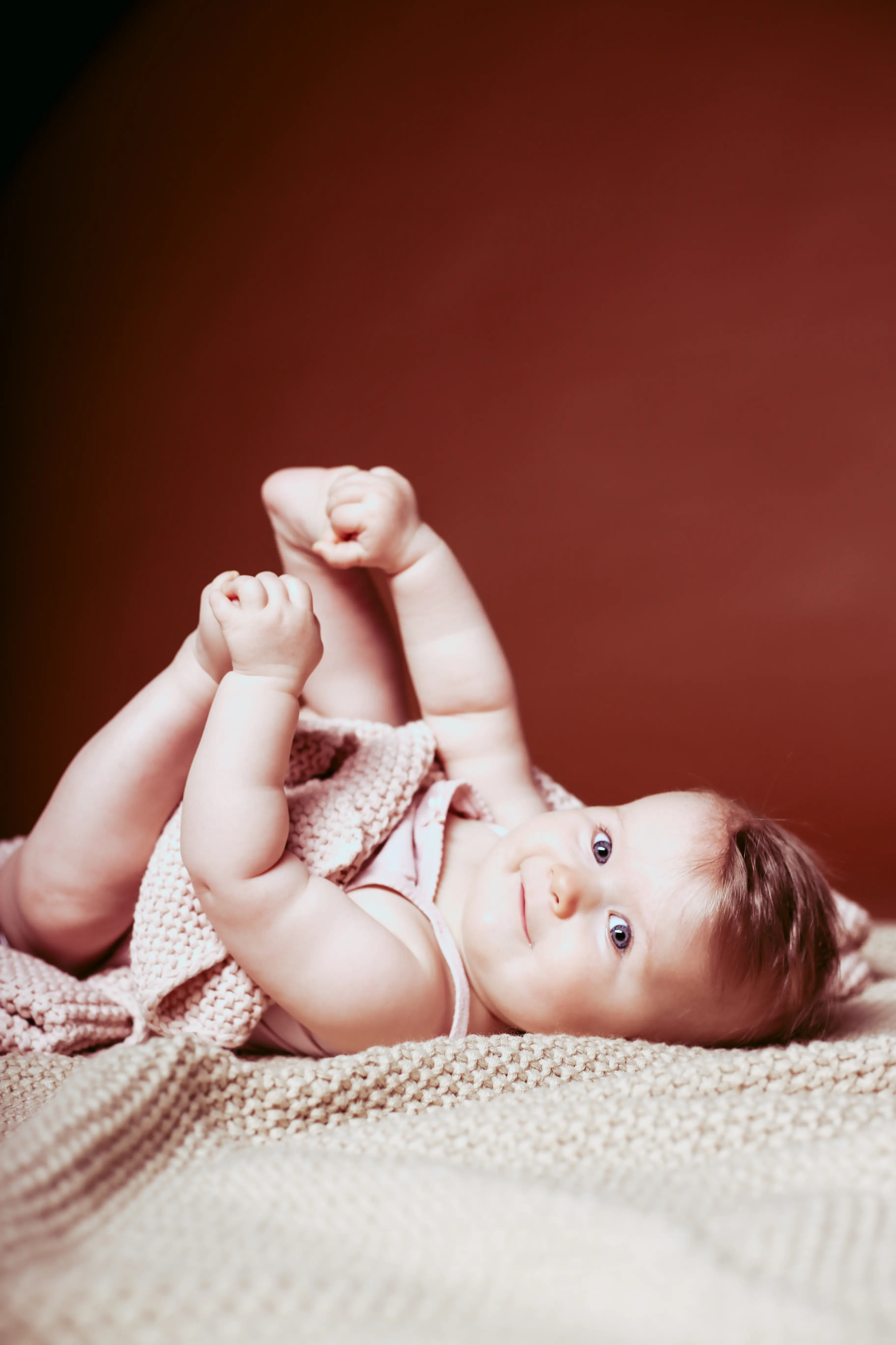 Baby auf Strickdecke mit neugierigem Blick