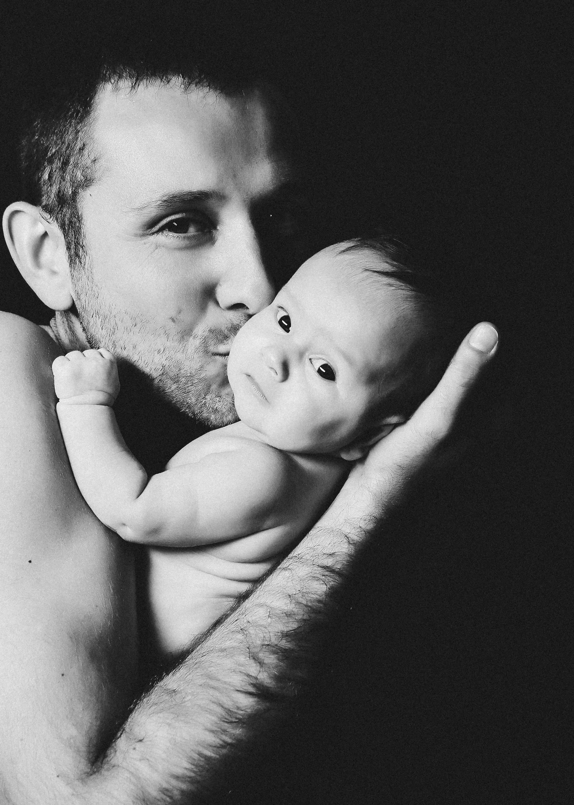 Vater kuschelt liebevoll mit Neugeborenem