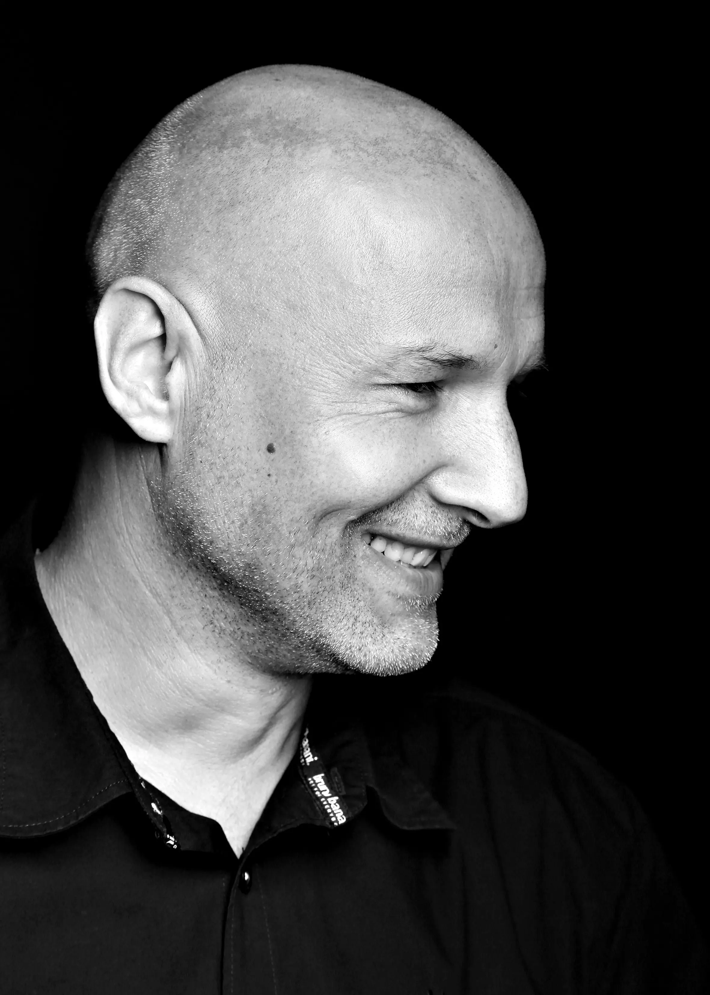 Mann mit Glatze lachend im Profil